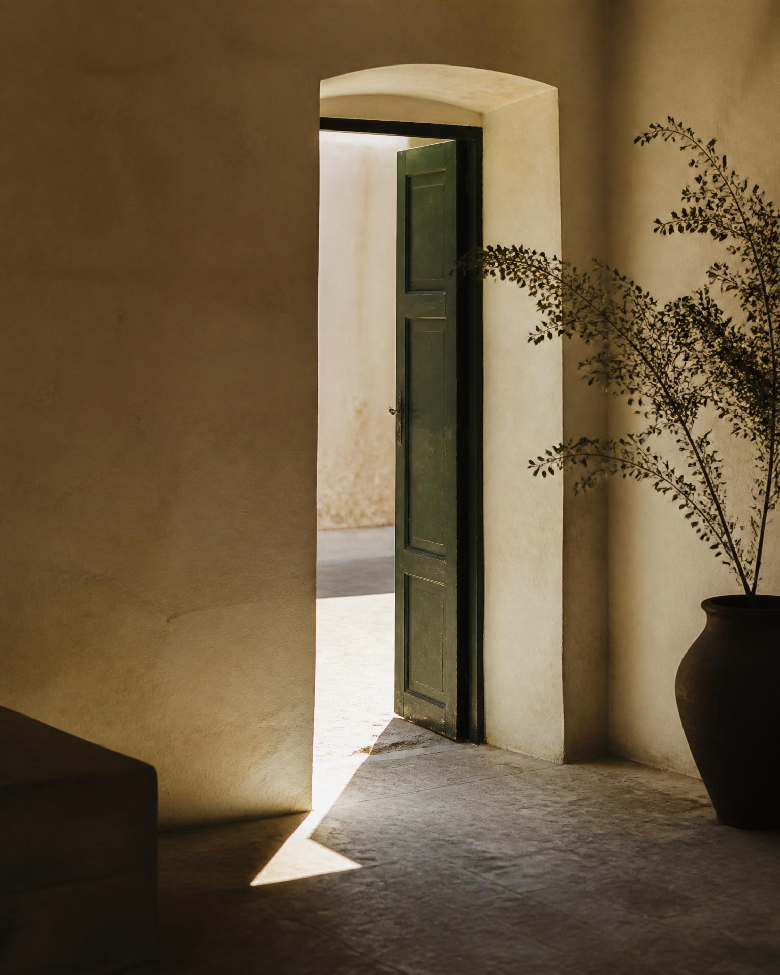 An open doorway in a warm plaster wall with daylight coming through